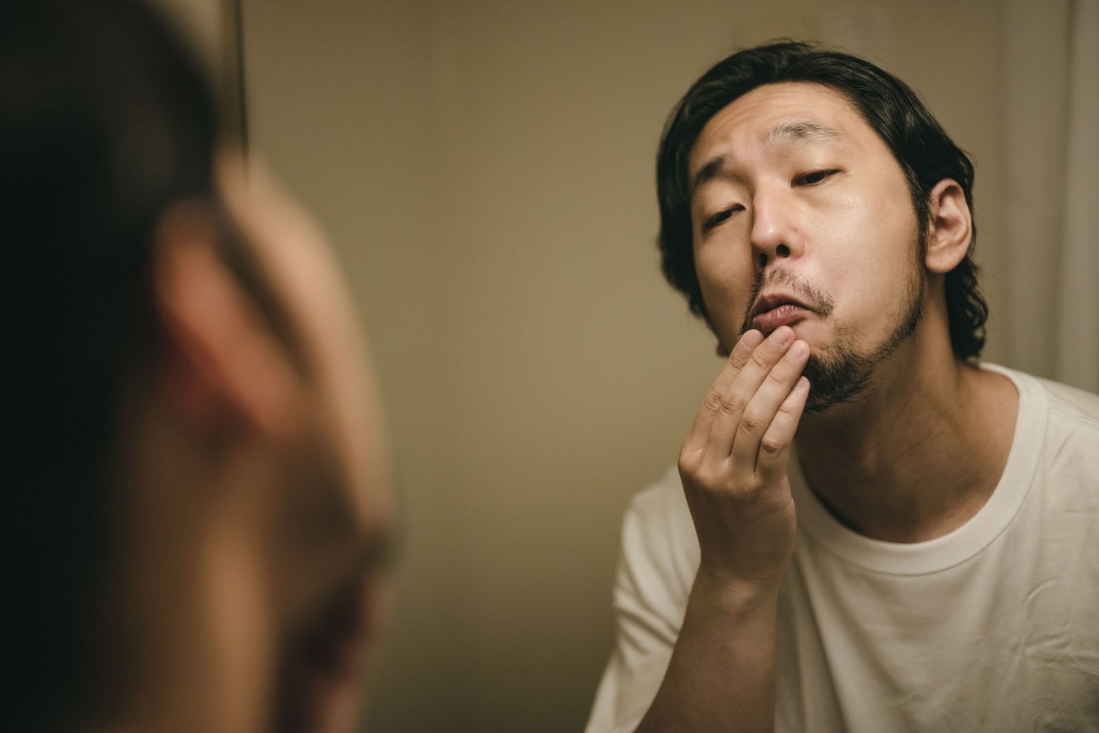 「髭を整えながら顔を歪める男性」の写真［モデル：大川竜弥］