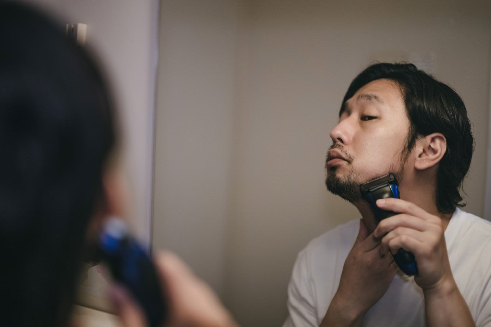 「鏡を見ながらシェーバーで髭剃り中」の写真［モデル：大川竜弥］