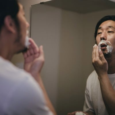 シェービングクリームを髭に付ける男性の写真