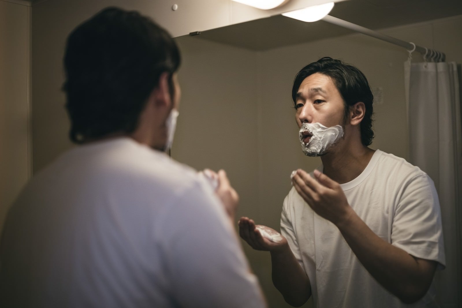 「口元にシェービングクリームをべったり塗り付ける男性」の写真［モデル：大川竜弥］