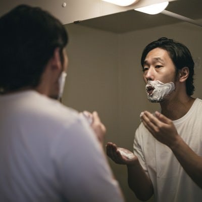 口元にシェービングクリームをべったり塗り付ける男性の写真