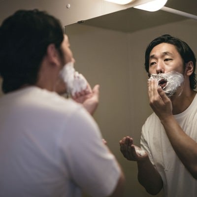 鼻下にシェービング剤を塗り込む男性の写真