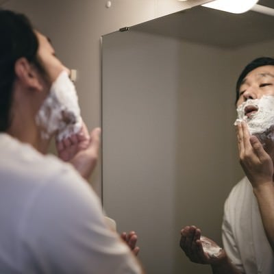 髭剃り用の泡を顔に塗る男性の写真
