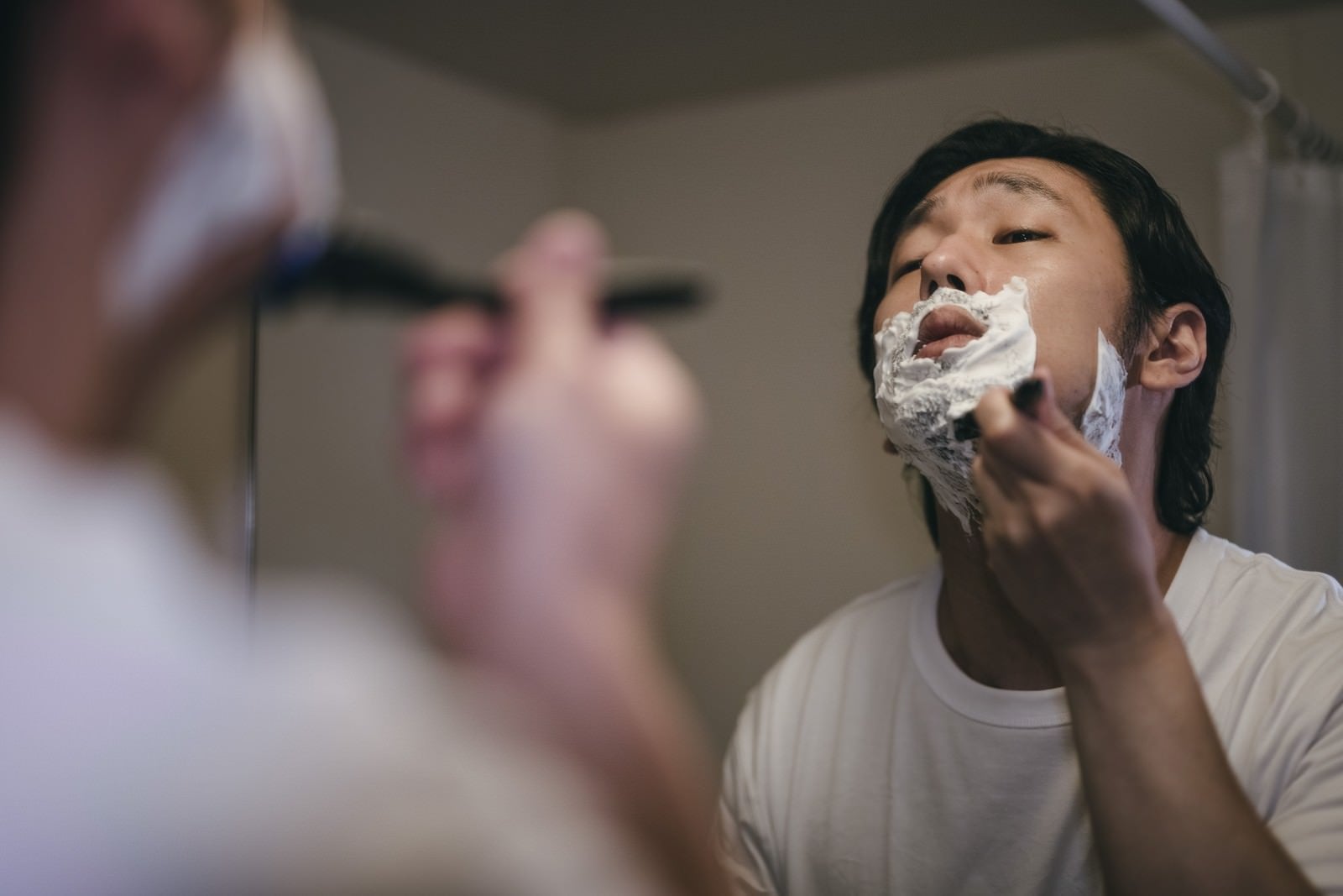 「顎の下を入念に剃り上げる男性」の写真［モデル：大川竜弥］