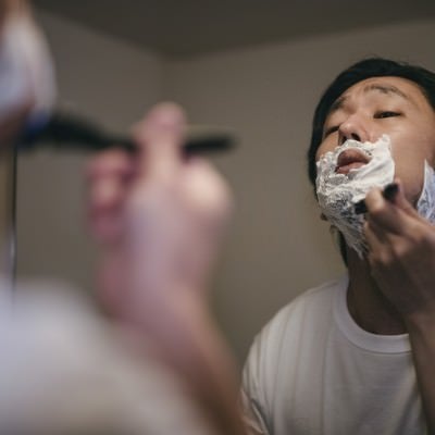 顎の下を入念に剃り上げる男性の写真