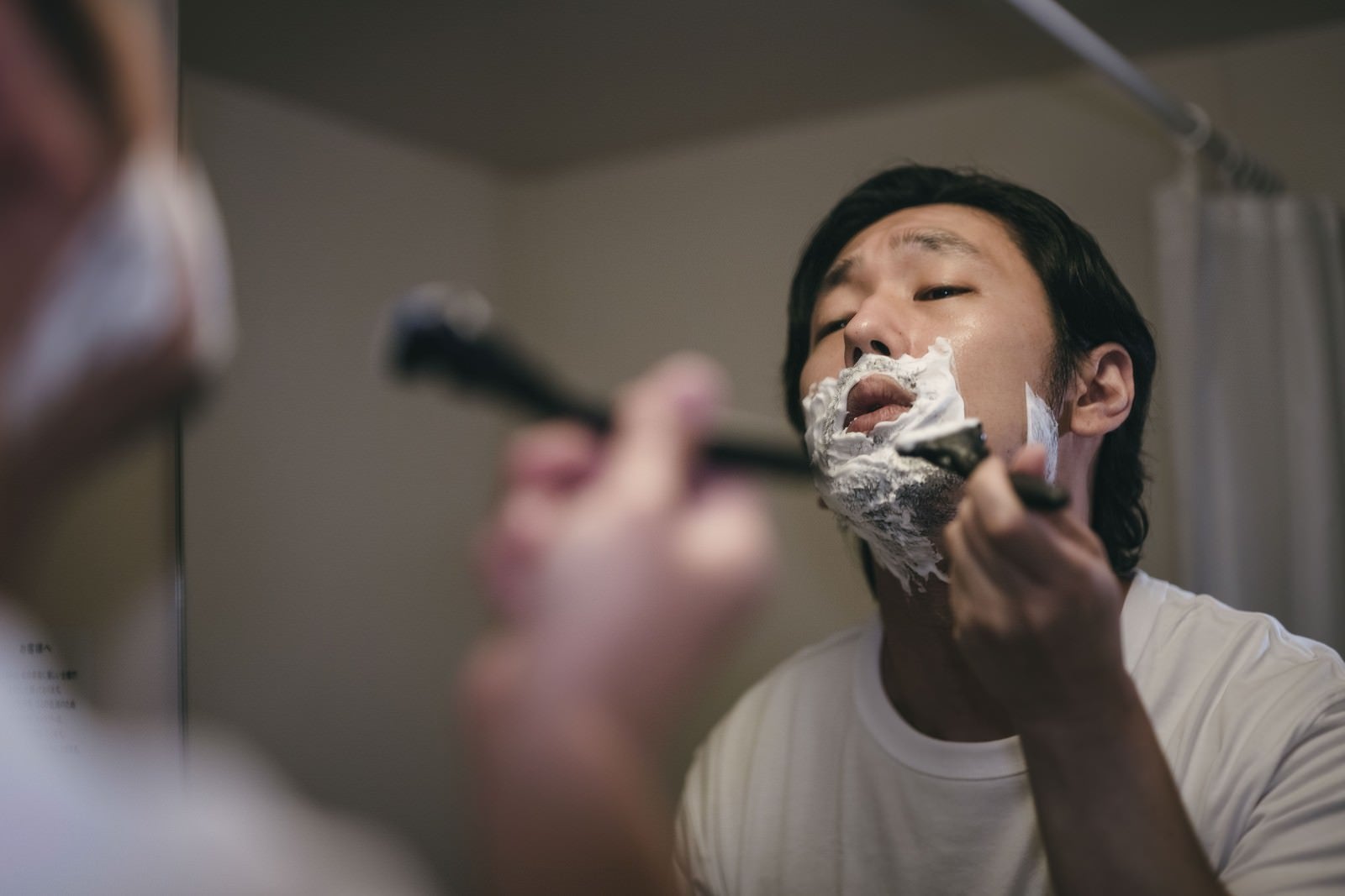 「左の頬から剃り始める男性」の写真［モデル：大川竜弥］