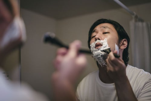 シェービング用の泡でで髭剃りする男性の写真