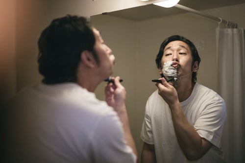 口をとがらせ首元を剃り上げる男性の写真