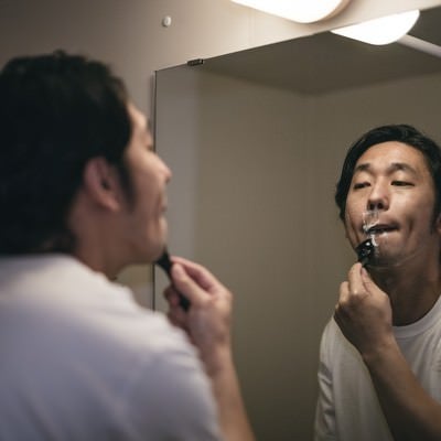 バスルームで髭剃りをする男性の写真