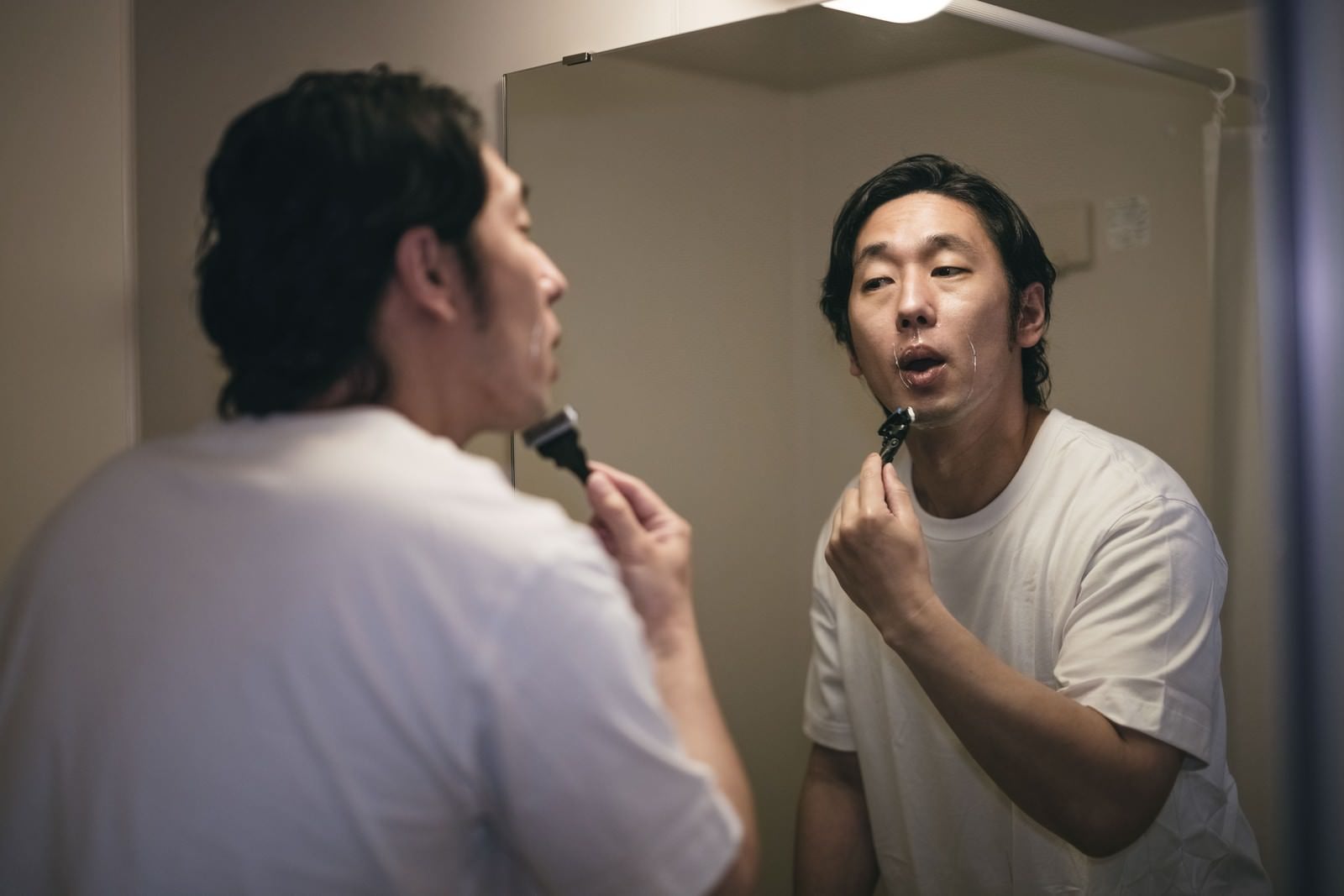 「髭剃りの仕上げを念入りに行う男性」の写真［モデル：大川竜弥］