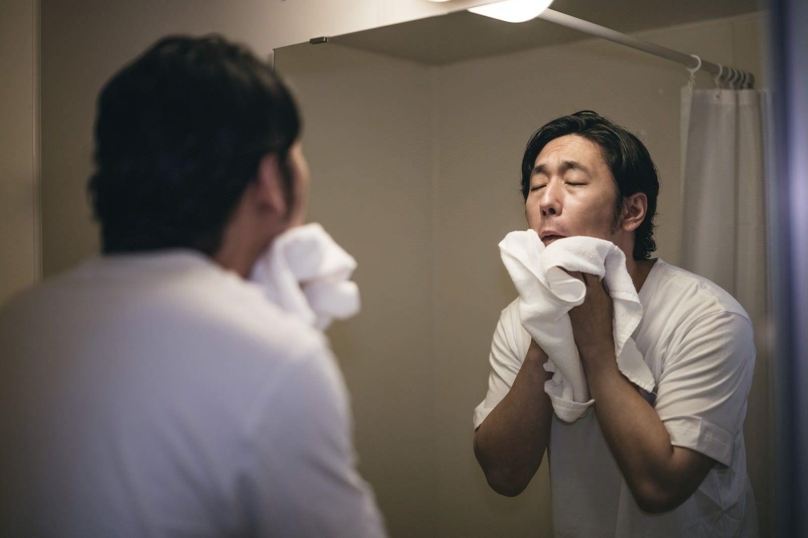 「白いタオルで顔を拭く男性」の写真［モデル：大川竜弥］