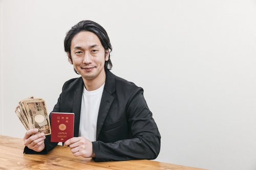 パスポートとお札を手に取る男性の写真