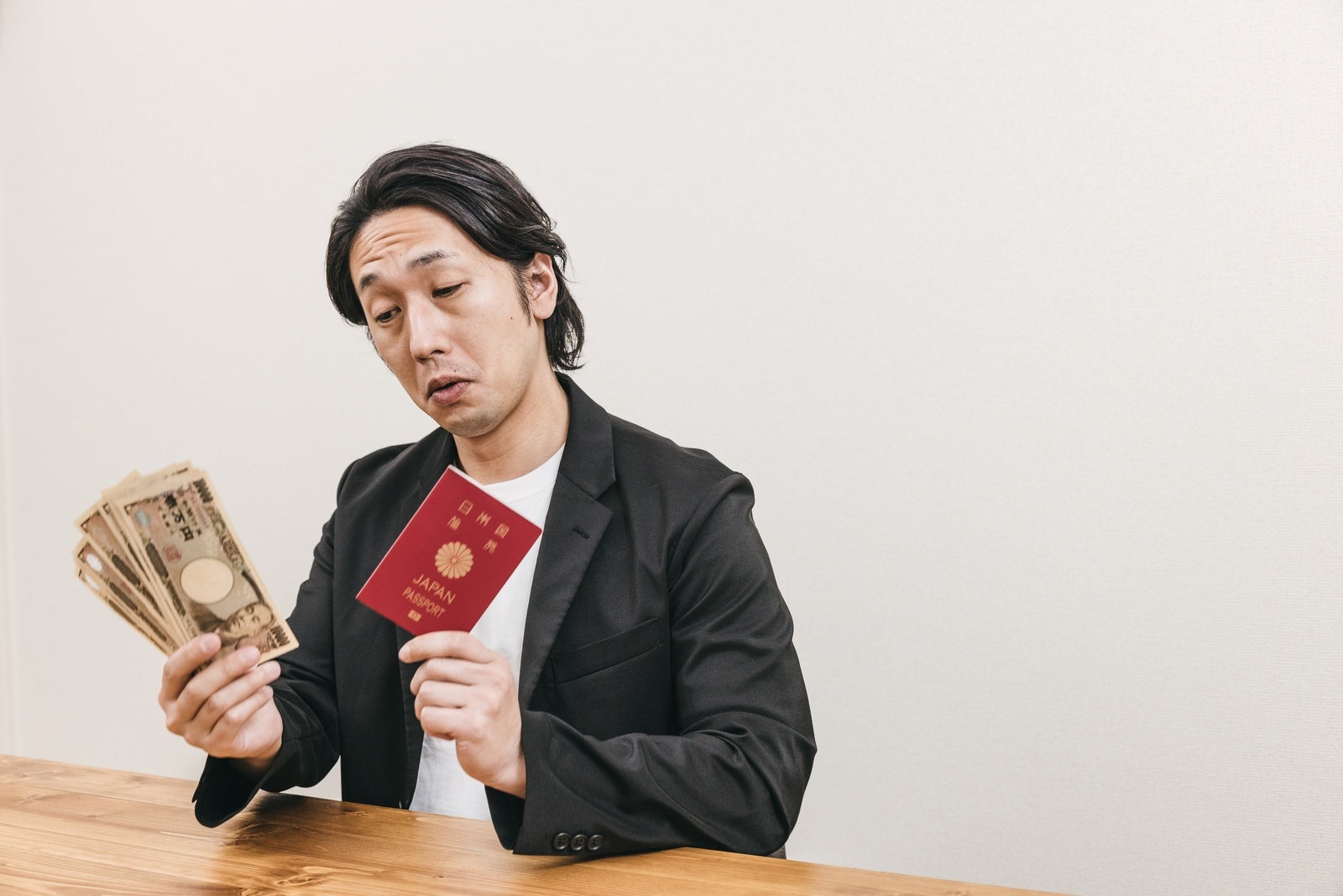 「紙幣と旅券を持った太々しい態度の男性」の写真［モデル：大川竜弥］