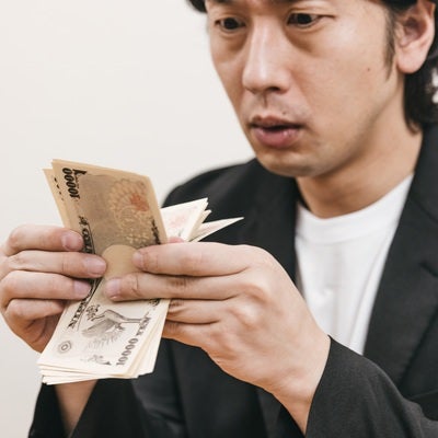 必死に紙幣を札勘する男性の写真
