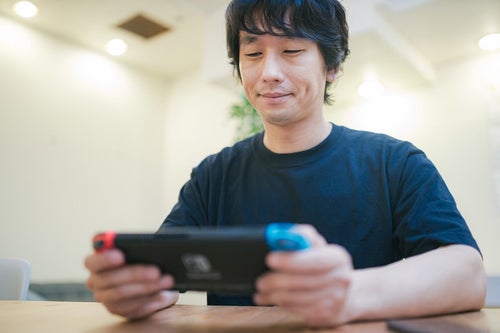 自宅で人気の携帯ゲーム機で遊ぶ男性の写真