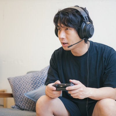 リビングでオンラインゲームをプレイする男性の写真