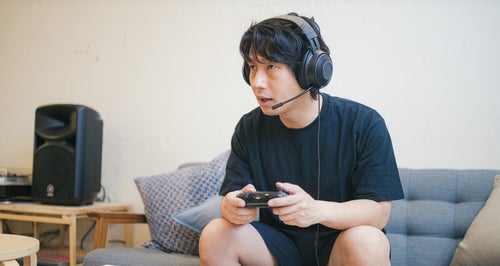 リビングでオンラインゲームをプレイする男性の写真