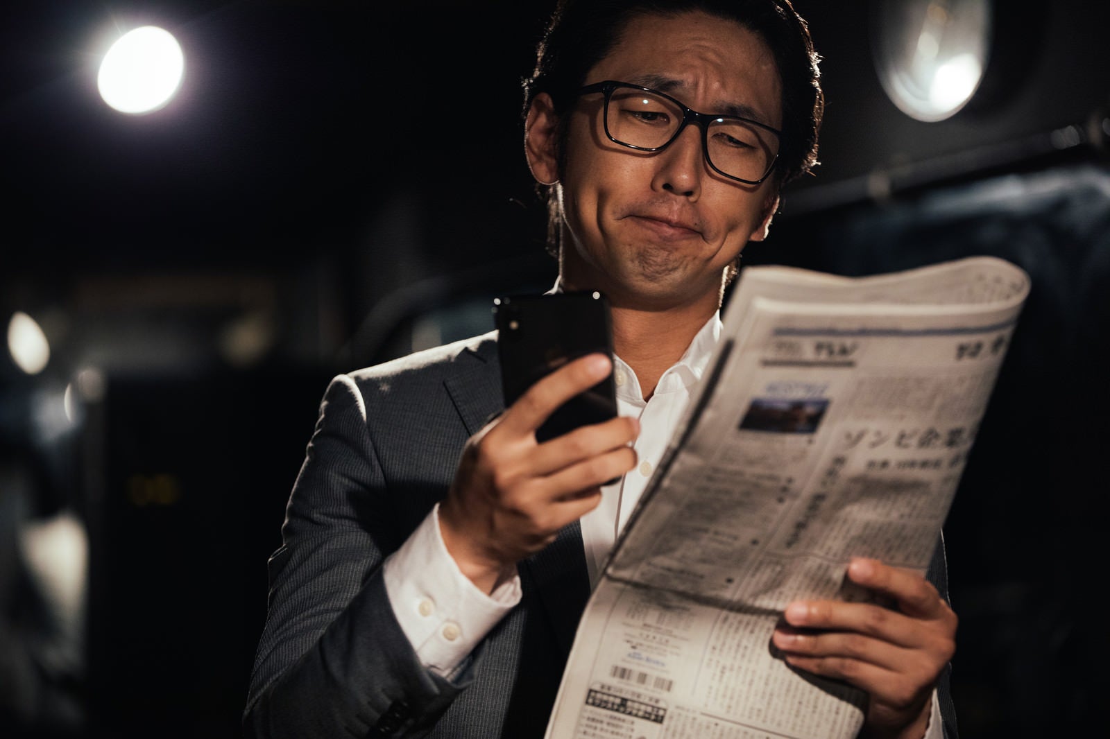 「紙面と電子版を同時にチェックするビジネスマン」の写真［モデル：大川竜弥］
