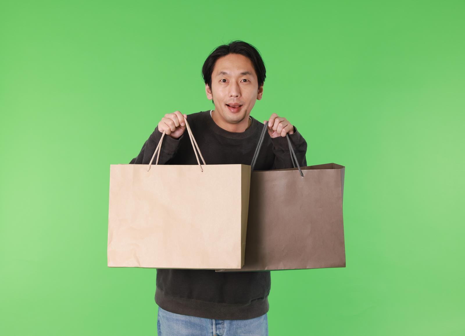 「両手に買い物袋を持った男性（グリーンバック）」の写真［モデル：大川竜弥］