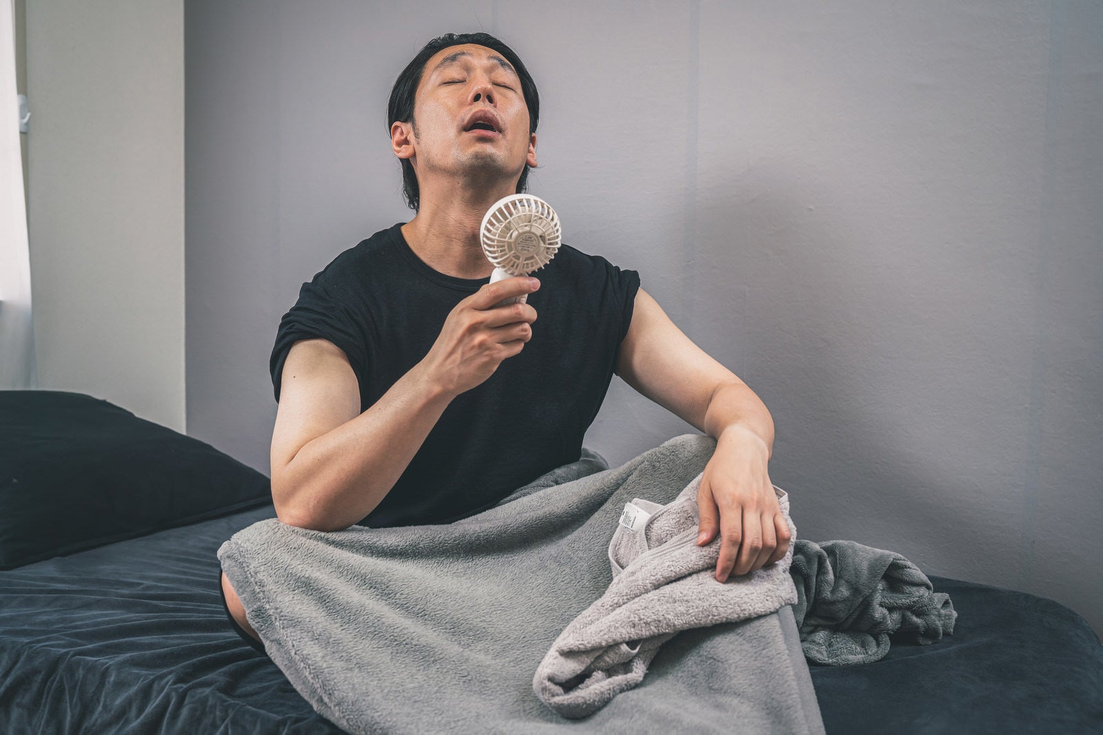 「節電対策にハンディ扇風機で涼む男性」の写真［モデル：大川竜弥］