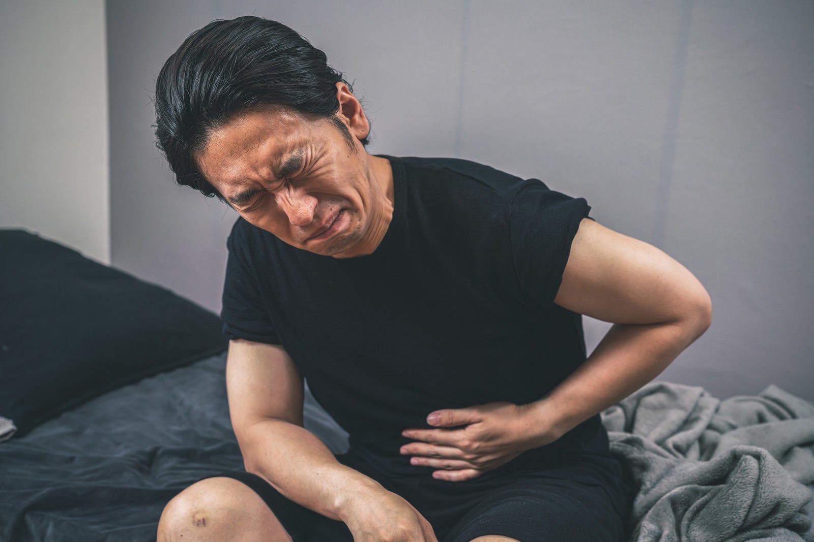 「冷房病で腹痛に苦しむ男性」の写真［モデル：大川竜弥］