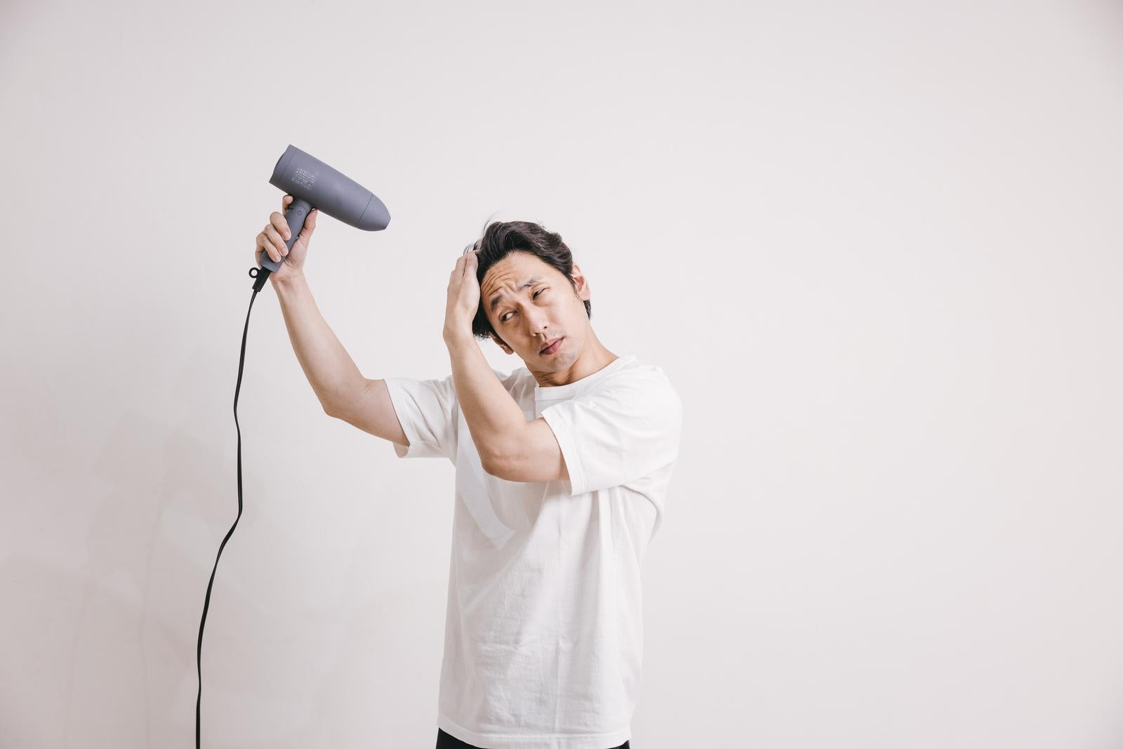 「ドライヤーを使って髪を乾かす男性」の写真［モデル：大川竜弥］