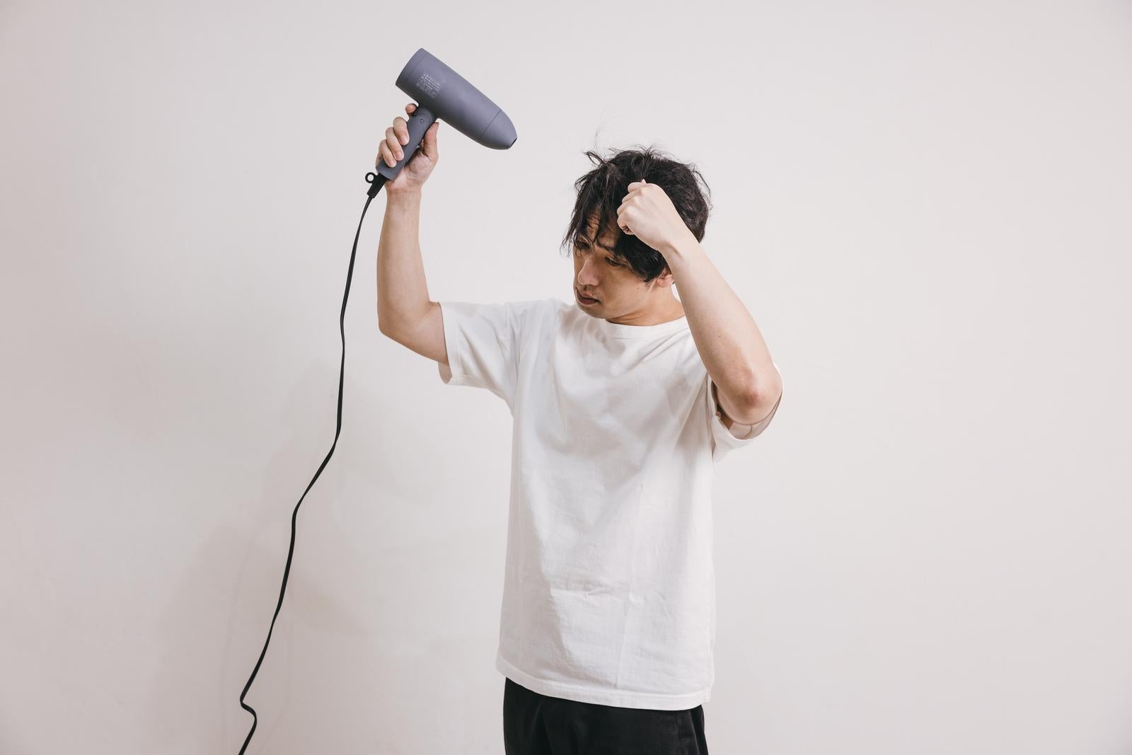 「髪の毛をブローする男性」の写真［モデル：大川竜弥］