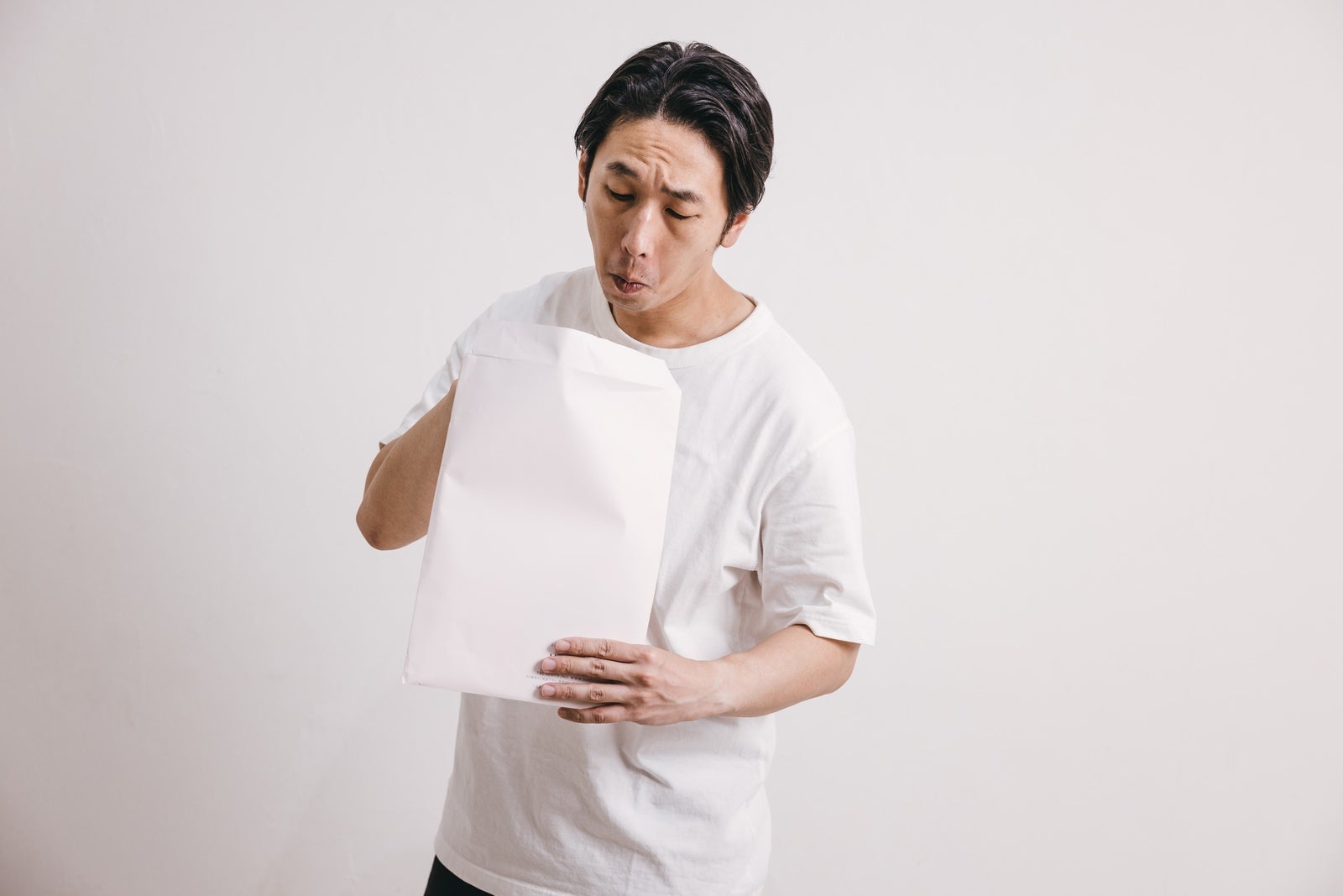 「白い封筒を開ける男性」の写真［モデル：大川竜弥］