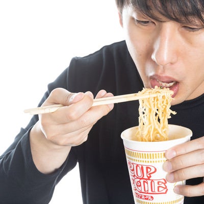 自粛中にカップ麺を食べる男性の写真