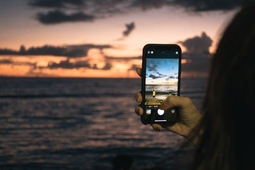 スマホで夕焼けと波打ち際を撮影するの写真