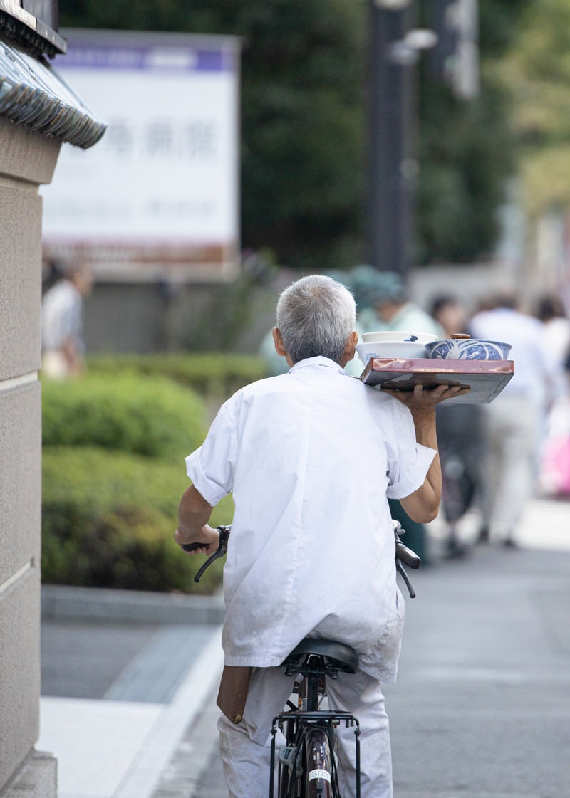 「片手で出前を運ぶ職人」の写真