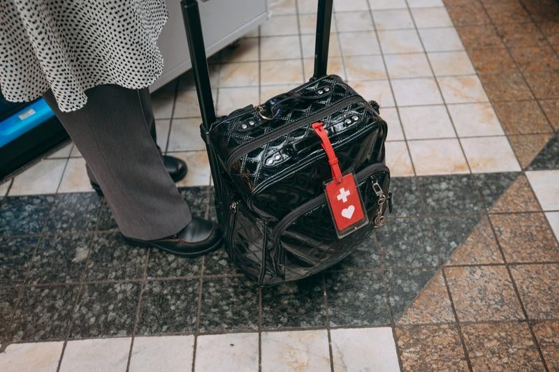 ヘルプマーク付きキャリーケースを引く女性の様子の写真