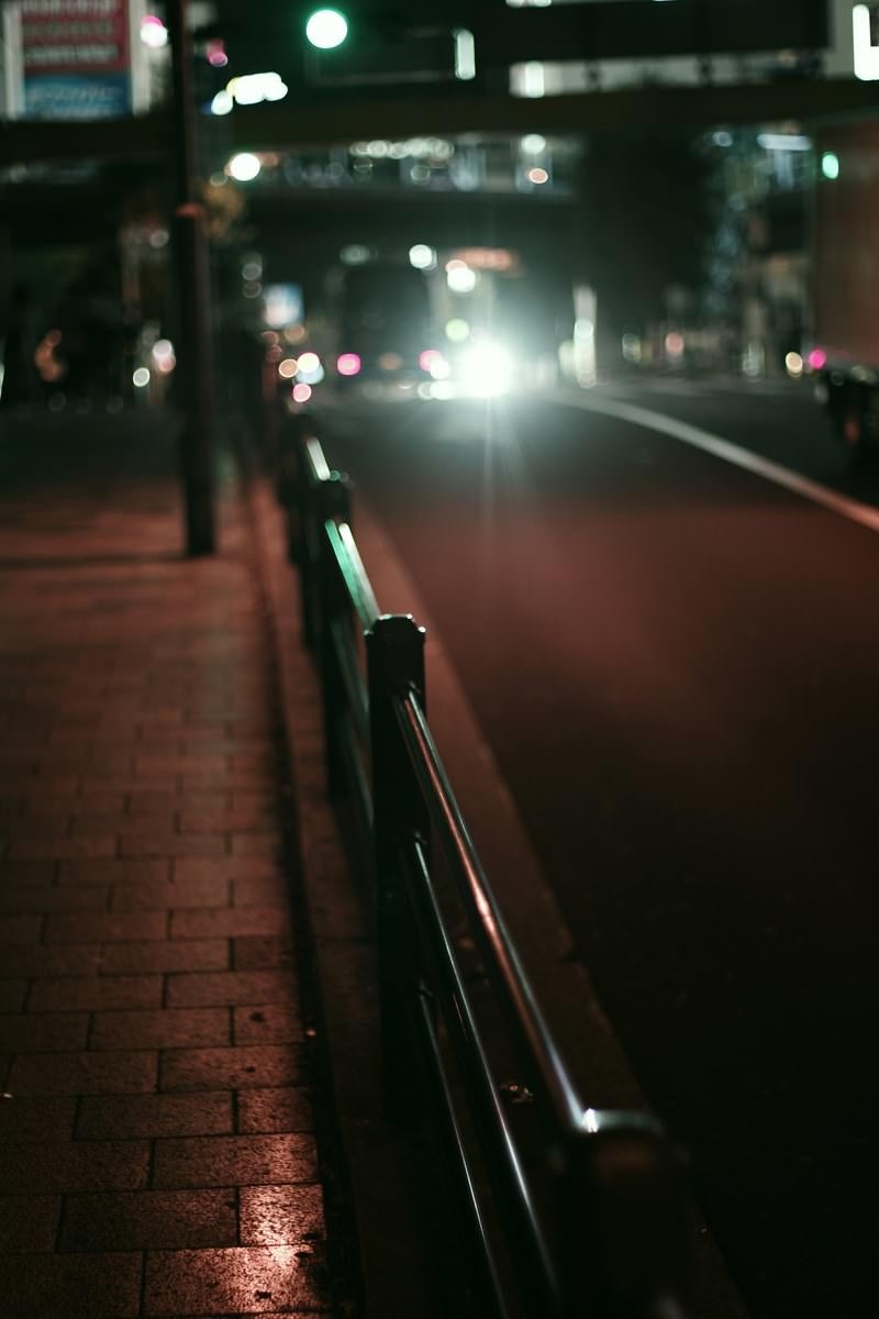 「夜のガードレールと車のハイビーム」の写真