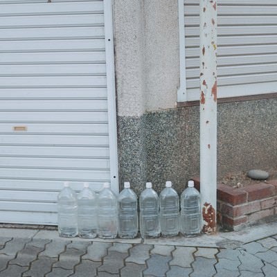街角に置かれた猫除けのペットボトルの写真