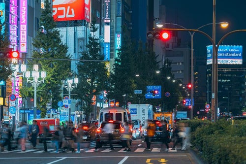 新宿区役所前の横断歩道を渡る人（夜間）の写真
