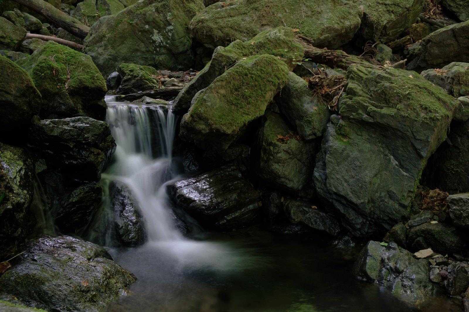 「険しい山道の岩場と小さな滝」の写真