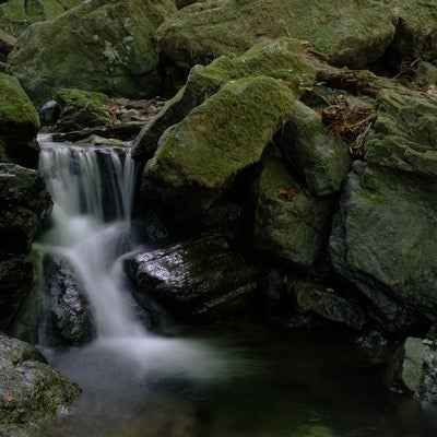 険しい山道の岩場と小さな滝の写真