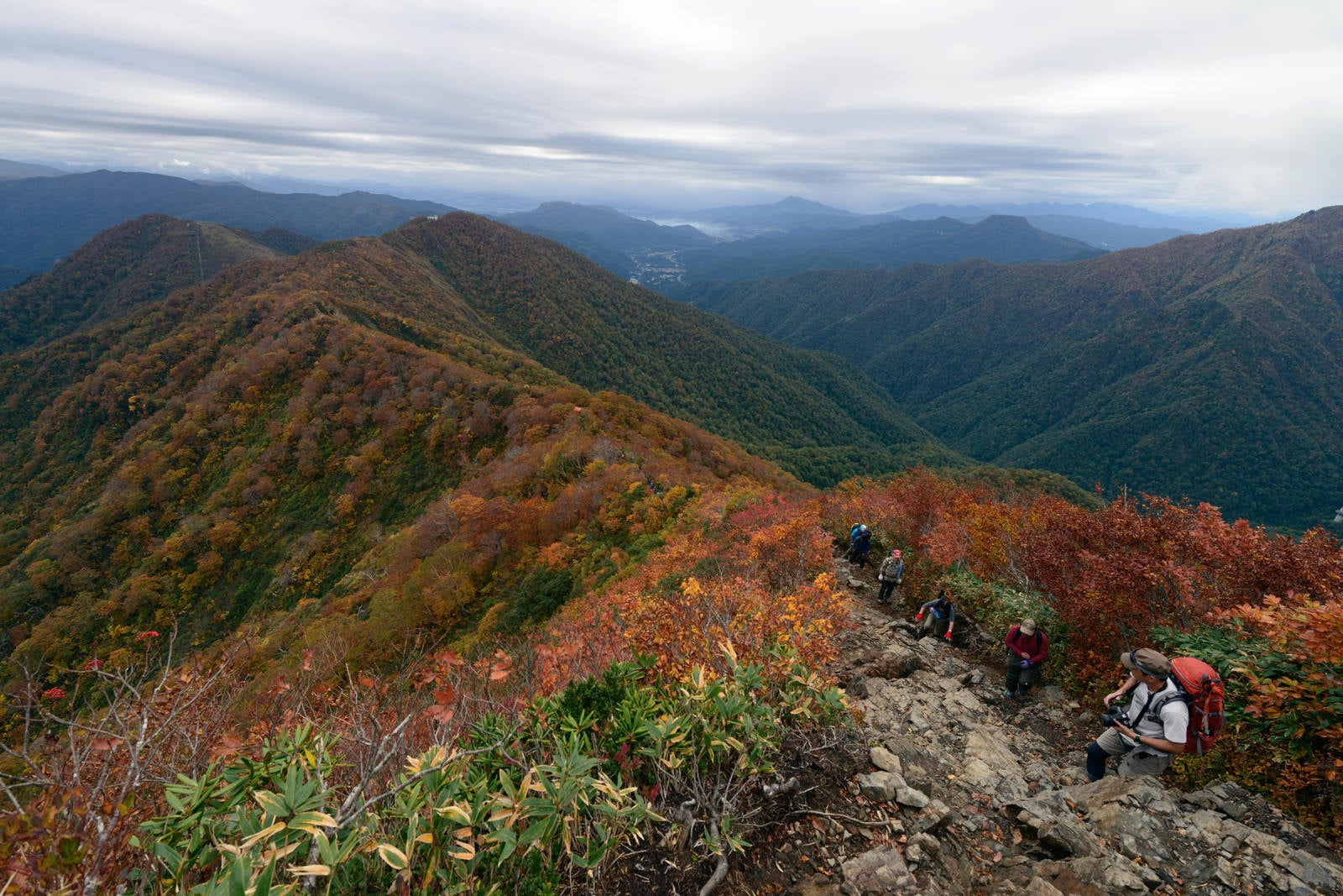 「紅葉する谷川岳の稜線を歩く登山者」の写真