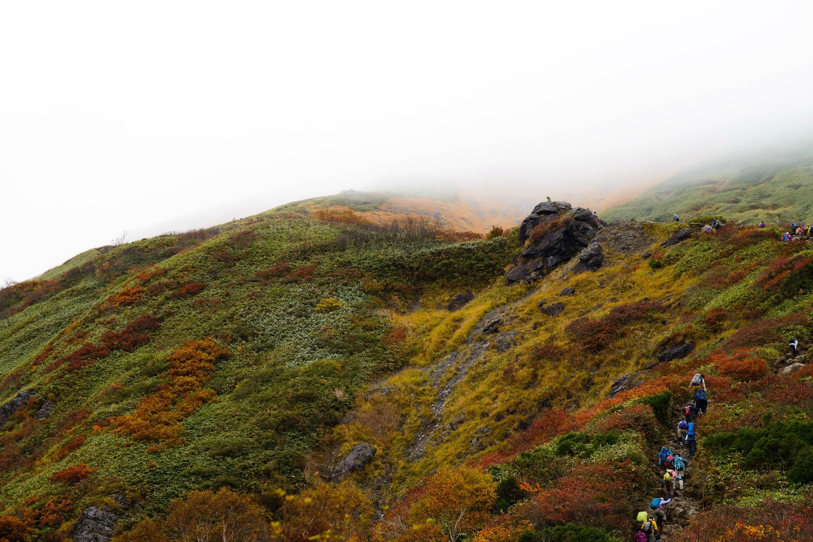 「黄葉する秋の谷川岳と登山者の姿」の写真