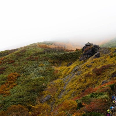 黄葉する秋の谷川岳と登山者の姿の写真