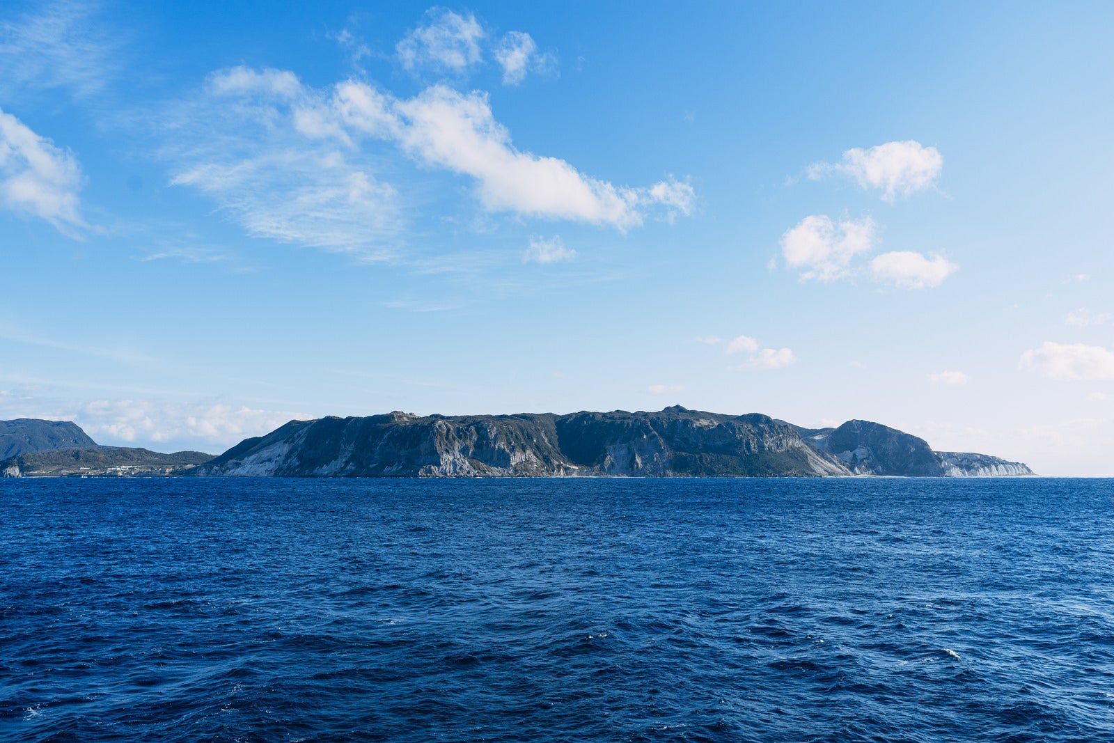 「陸地の緑と海水の蒼、海上から見ると壮大で荘厳な伊豆大島」の写真
