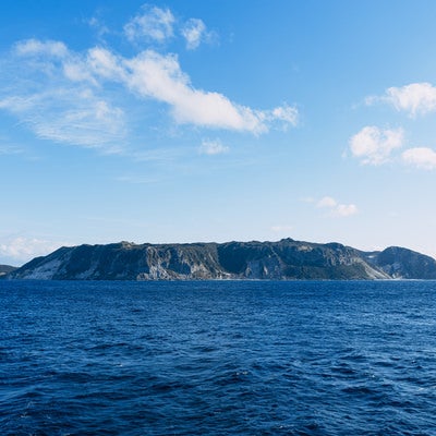 陸地の緑と海水の蒼、海上から見ると壮大で荘厳な伊豆大島の写真