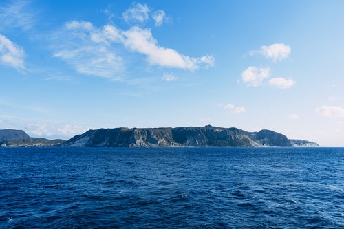 陸地の緑と海水の蒼、海上から見ると壮大で荘厳な伊豆大島の写真