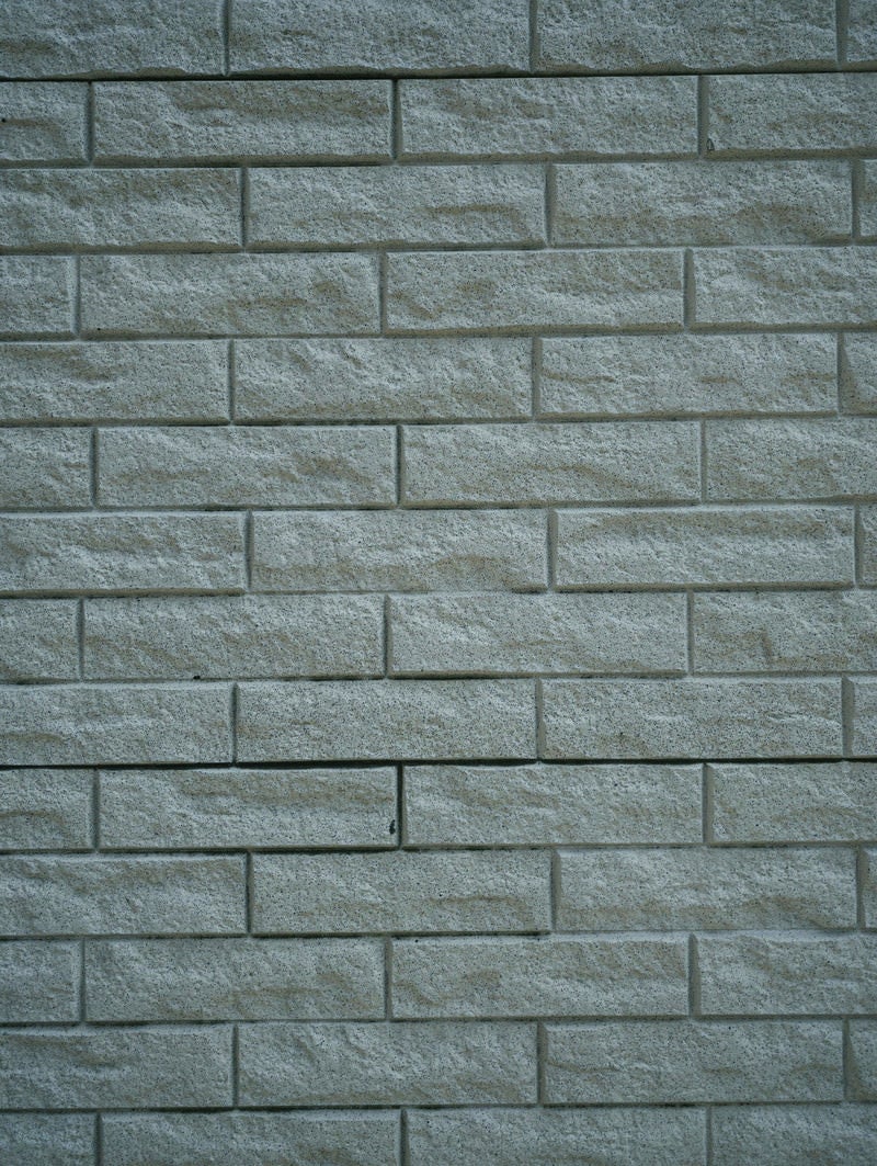 「凹凸のあるブロックタイルが敷き詰められた壁（テクスチャー）」の写真