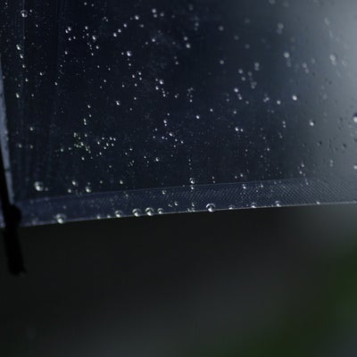 透明な傘に残る雨のしずくの写真