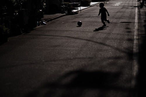 路上でボールを使って遊ぶ子供に注意の写真