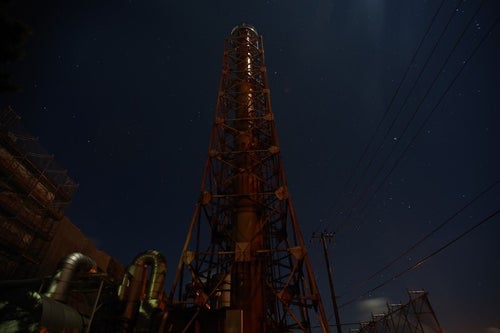 工場の煙突とまばらな星空の写真