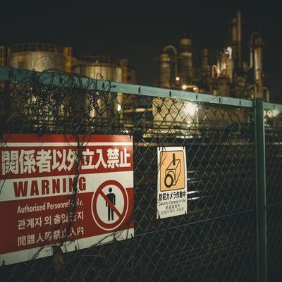 立入禁止のフェンス越しに望む工場夜景の素材