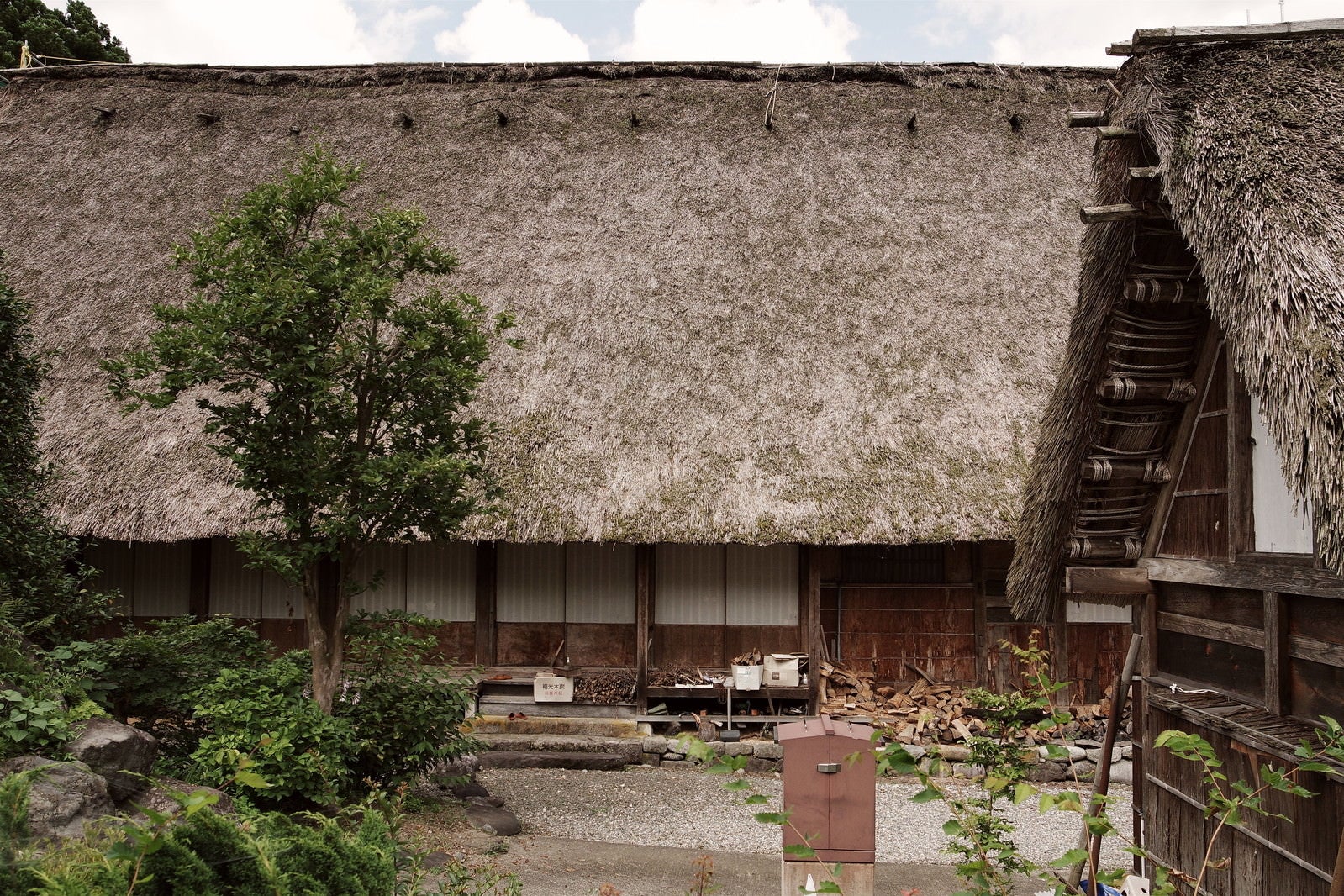 「茅葺屋根と軒下の薪（富山県南砺市）」の写真