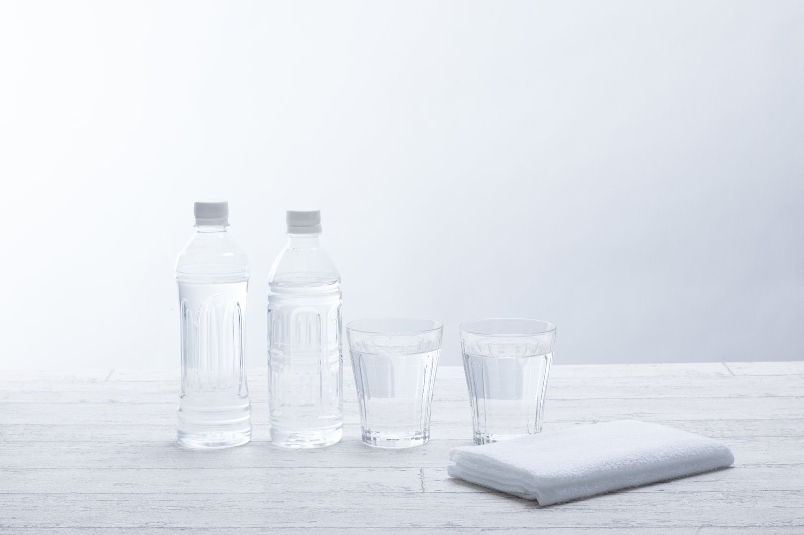 「ミネラルウォーターのボトルとグラスの水」の写真